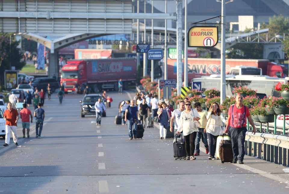 Tourists leave a Turkish airport carrying their luggage after it was overrun by the military