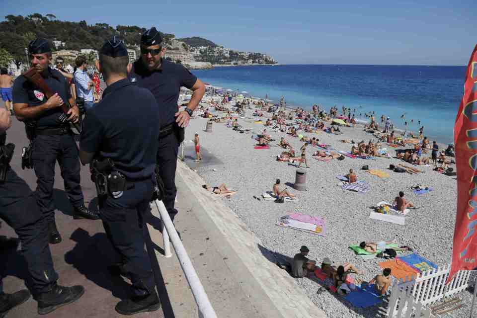 French CRS police patrol on the walkway above a public beach with sunbathers as security measures continue after the Bastille Day truck attack by a driver who ran into a crowd on the Promenade des Anglais that killed scores and injured as many, in Ni