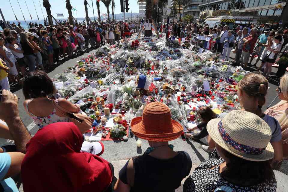 People gather near flowers placed at a m