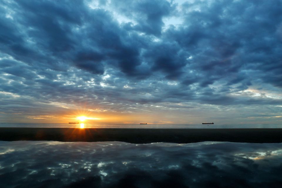 Three ships sit off the North East Coast near Tynemouth at sunrise as forecasters predict that the mercury will soar to the mid-30s this week