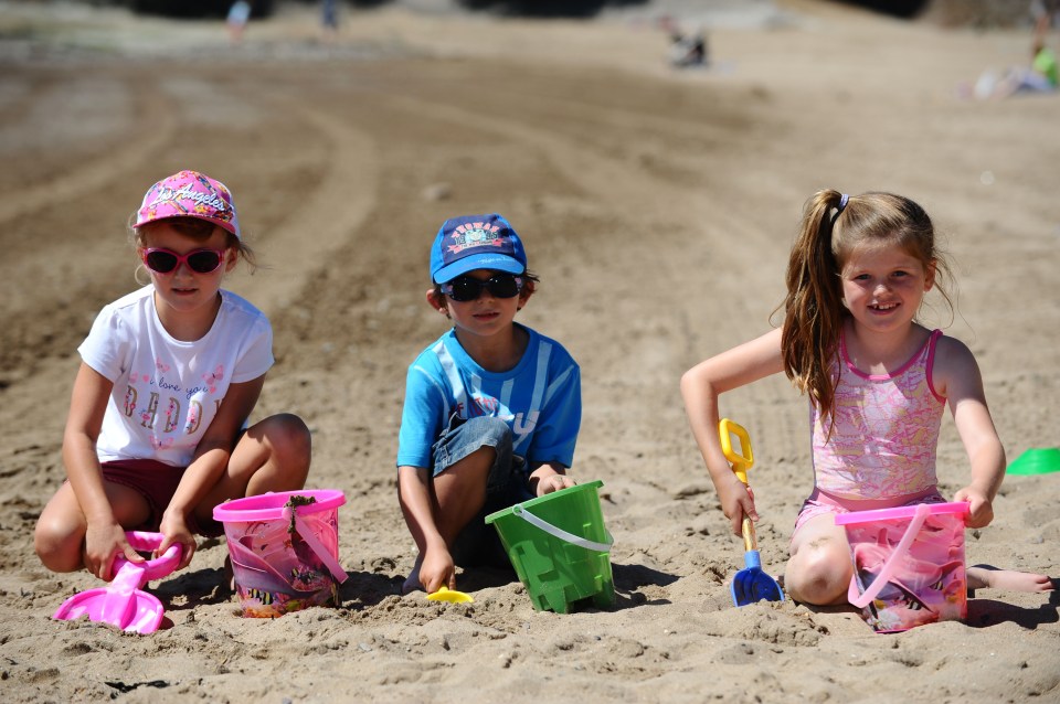 Ava Rose Manly age 7, Zane Warmsley age 7 and Frankie Rose Shoemark age 7 make sandcastles on the beach at Barry Island in South Wales despite the morning sea mist