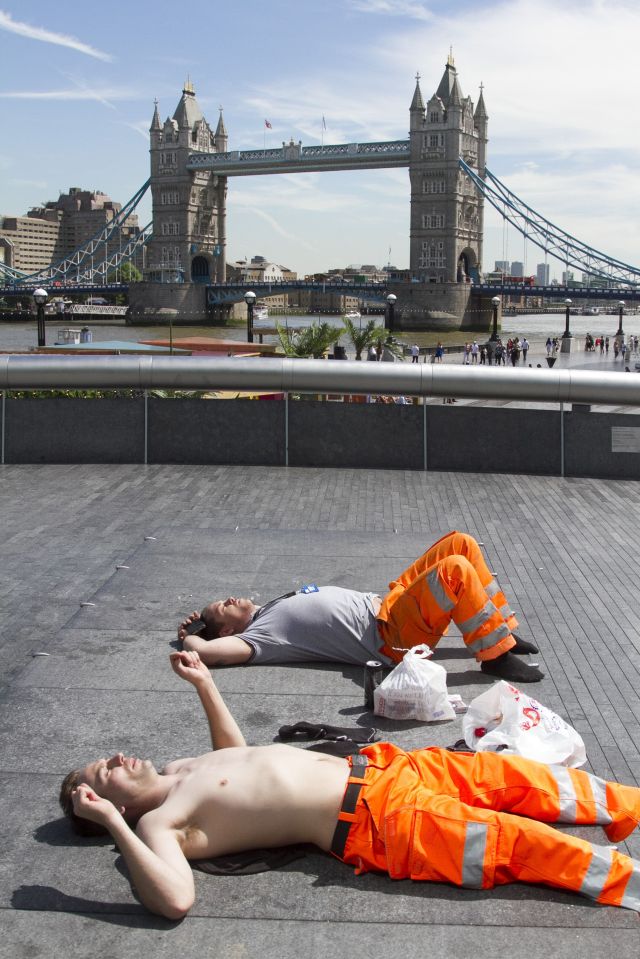 Workmen take a break and sunbathe on the ground in central London