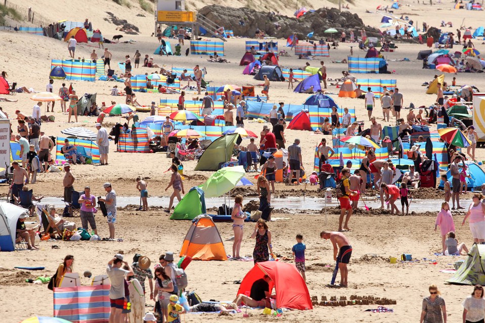 Thousands of people flock to the beach at Woolacombe in Devon as Britain's heatwave continues