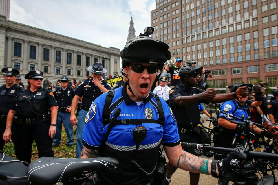 A policeman uses his bicycle to push back anti-Donald Trump protesters from pro-Trump supporters during the Republican National Convention in Cleveland