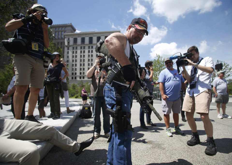 An unidentified man carrying a rifle and pistol is photographed by members of the media as the Republican National Convention is underway in Cleveland, Ohio