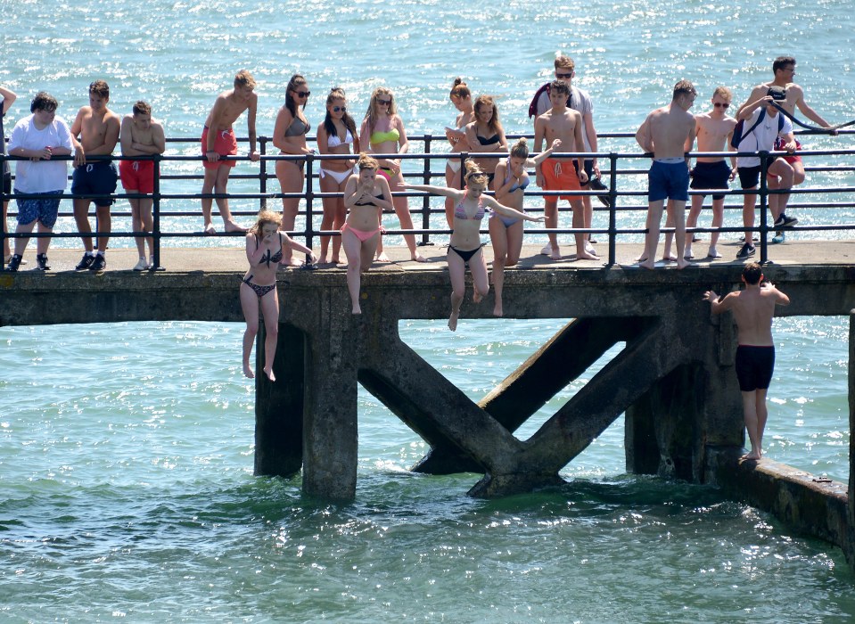 On the hottest day of the year so far in Portsmouth, Hampshire are youths cooling off by jumping into the sea off Victoria Pier at the Hot Walls beach in Old Portsmouth into shallow waters