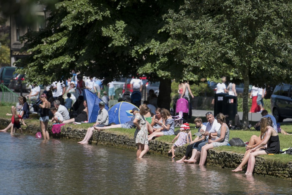Others dipped their toes in the cool trickling waters of the river in Bourton-on-the-water in Gloucestershire
