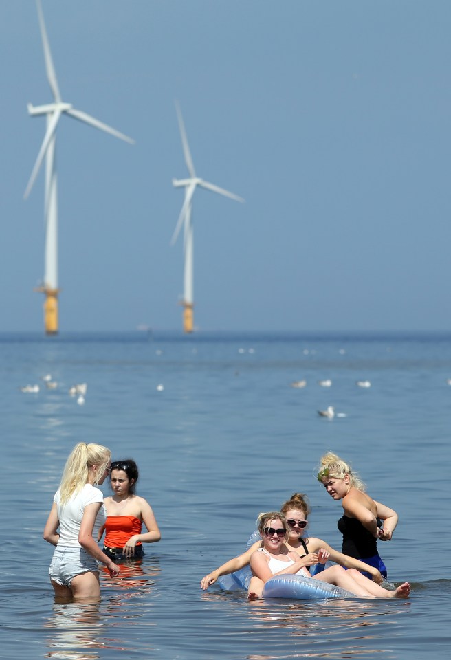 In Teeside people take to the beachfront to cool down with offshore wind turbines creating the backdrop