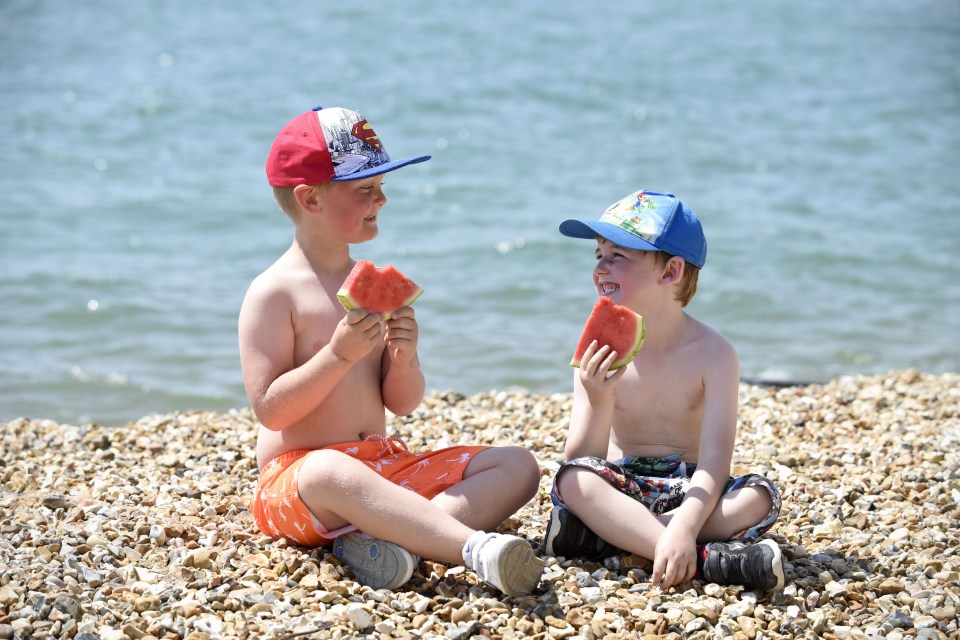 Ralf Strode, aged six, and Shay Spires, aged five, eat watermelon to cool down on Southsea beach