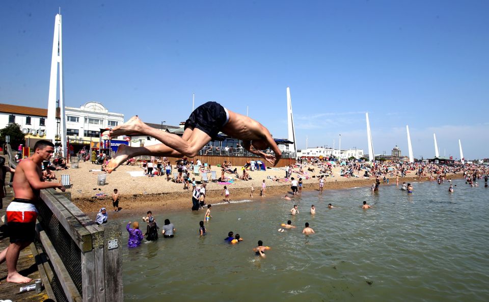 Joe Crawley from Milton Keynes jumps off a pontoon into the sea at South End on Sea, Essex