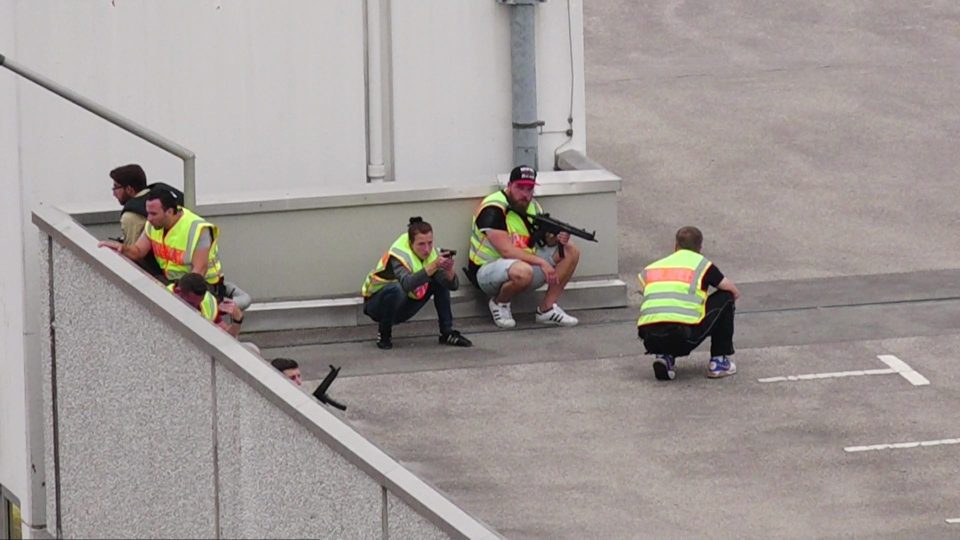 Armed police seen taking cover on a car park 