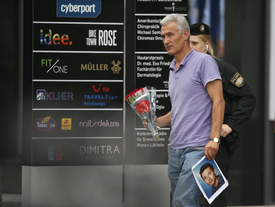 Man holding photo he claims is his slain son approaches police cordon near Olympia shopping mall in Munich