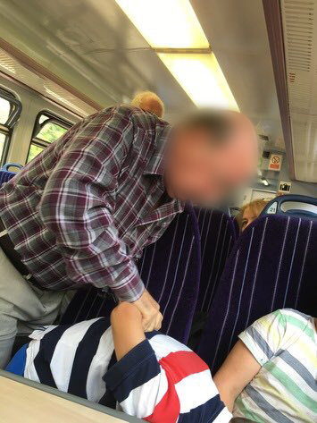 A man appears to put a young boy in an arm lock on a train
