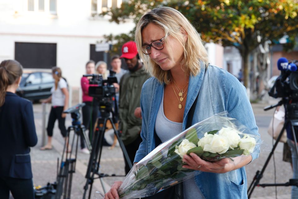 A woman lays flowers at the city hall in