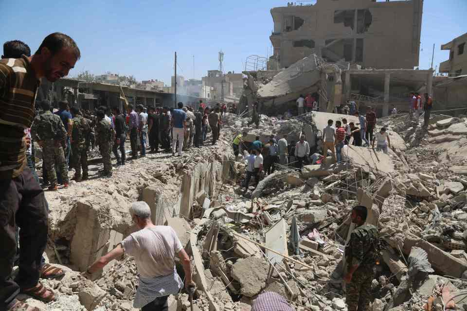Residents gather at the site of a bomb attack in Syria's northeastern city of Qamishli