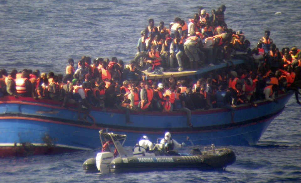 In this photo released by the Italian Navy on Monday, June 30, 2014, and taken on Sunday, June 29, 2014, a motor boat from the Italian frigate Grecale approaches a boat overcrowded with migrants in the Mediterranean Sea