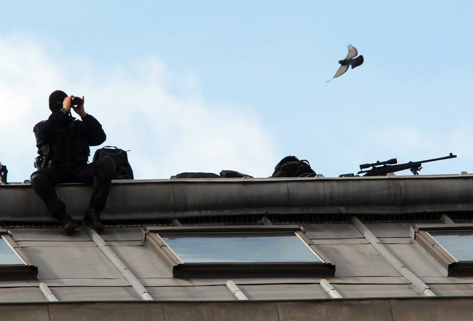 In this photo taken on Wednesday, July 27, 2016, a French police officers watches the festivities through binoculars on the roof of the town hall, during the opening night of the Bayonne festival