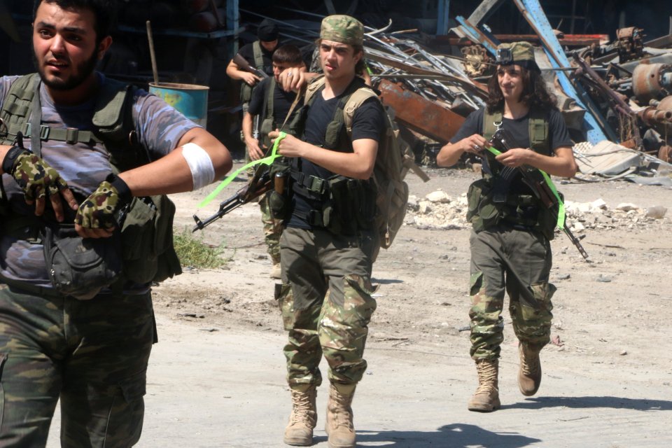 Free Syrian Army fighters walk with their weapons in Ramousah area southwest of Aleppo