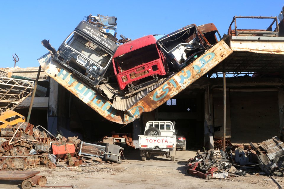 Damaged vehicles pile on a damaged roof of a car mechanic service center in Ramousah area southwest of Aleppo