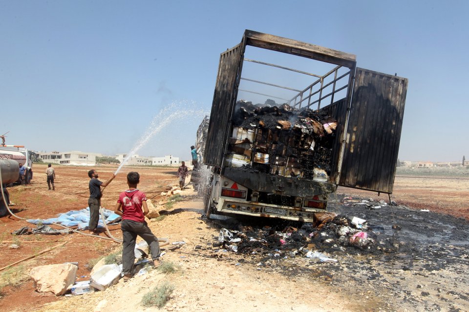 Men try to put out a fire of a loaded truck after an airstrike on a truck parking lot in the rebel-held town of Atareb in Aleppo province