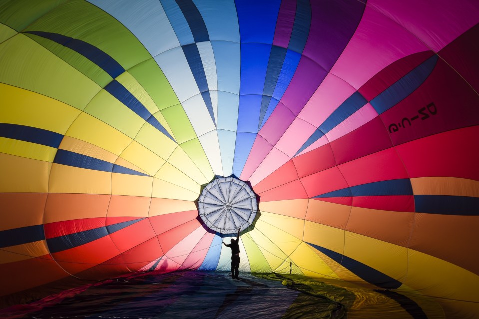 The morning sun shines through the fabric of a multicoloured balloon ahead of its launch this morning