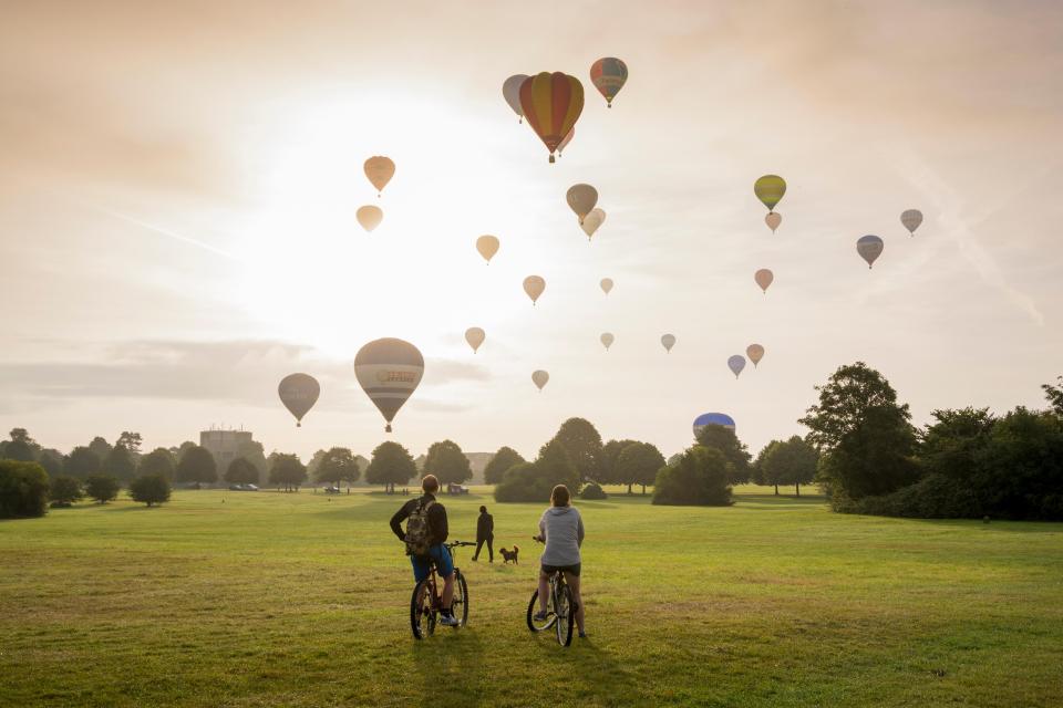 Cyclists stop to drink in the view as 30 hot air balloons rise into the Bristol skies 