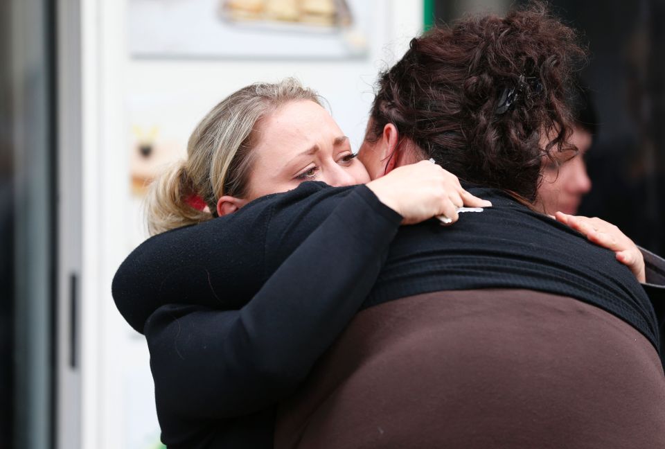 Women comfort each other outside the dam