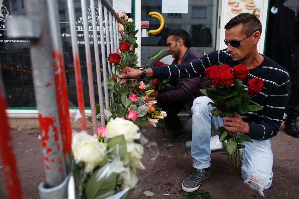 Men lay down flowers in front of a barri