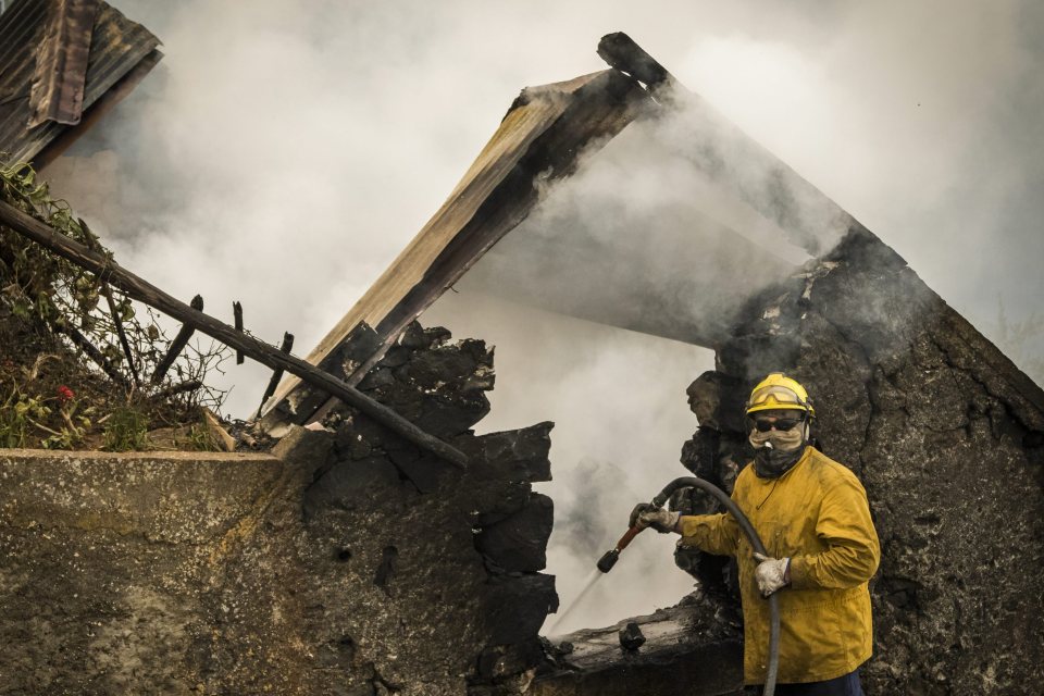 A fireman hoses down the smouldering remains of a destroyed house in the city of Funchal