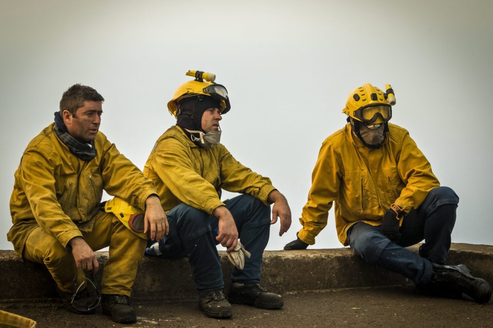 Exhausted firefighters were seen pausing for rest after battling the relentless flames throughout the night