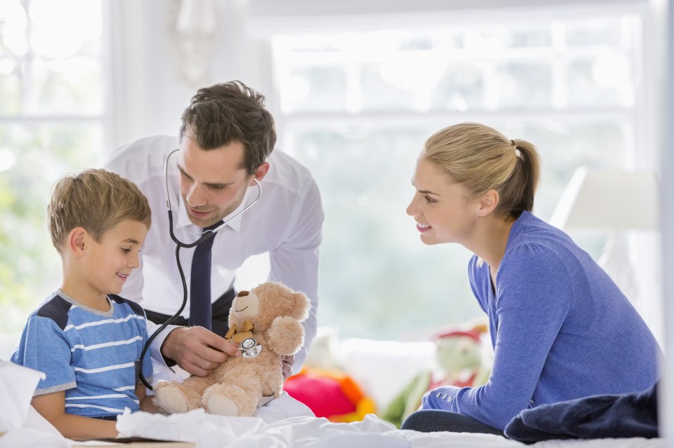 Doctor listening to teddy bear's heartbeat at house call