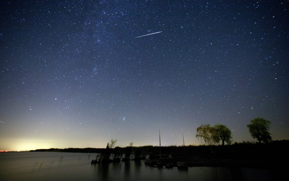 A picture taken with a slow shutter shows a meteor moving past stars in the night sky over lake Neusiedlersee near Moerbisch am See, around 70 km southeast of Vienna, Austria
