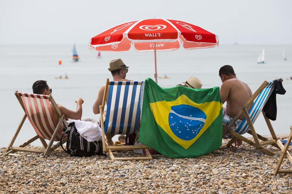 Sun worshippers get into the Olympic spirit on Brighton beach displaying a Brazilian flag as they soak up the sun