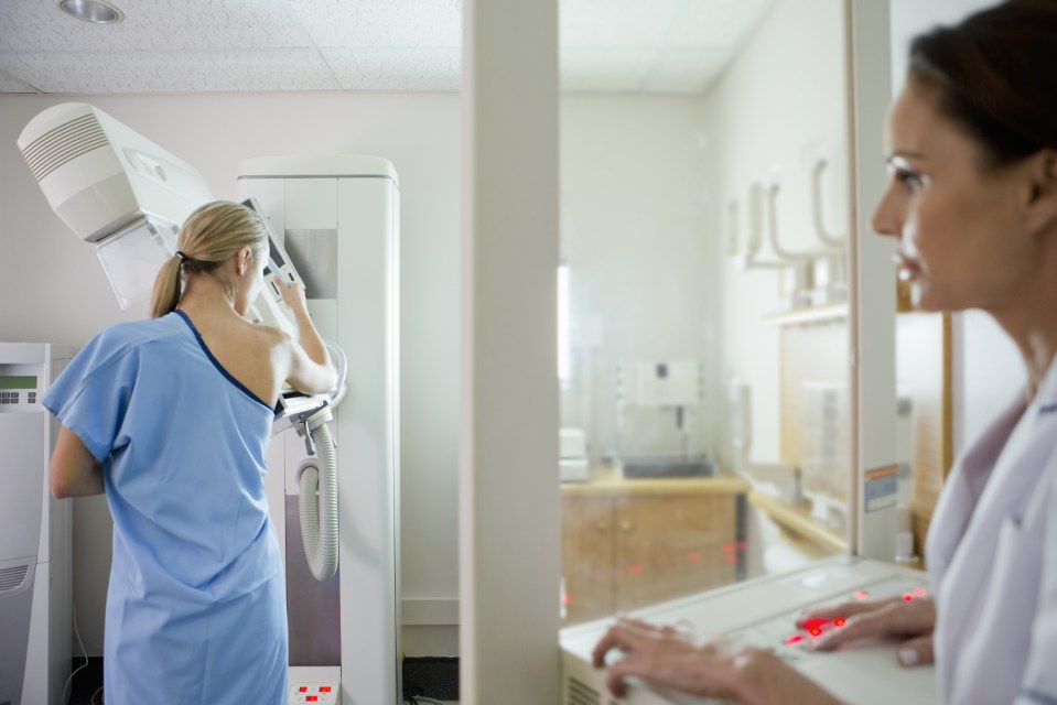 Patient undergoing mammogram at x-ray machine