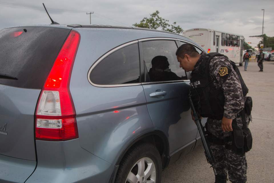 A cop inspects a vehicle during a checkpoint inspection near where the crime occurred