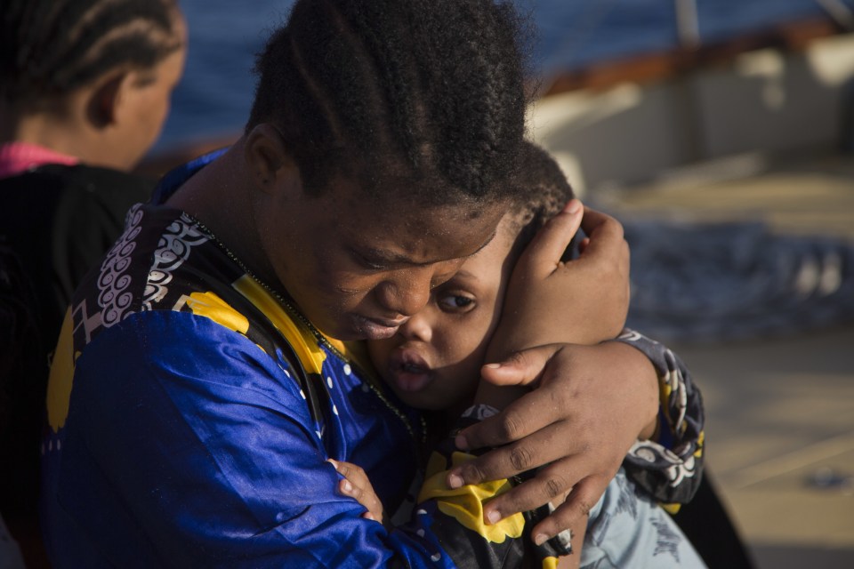 A woman from Nigeria comforts a child on the Astral vessel after been rescued by members of Proactiva Open Arms NGO