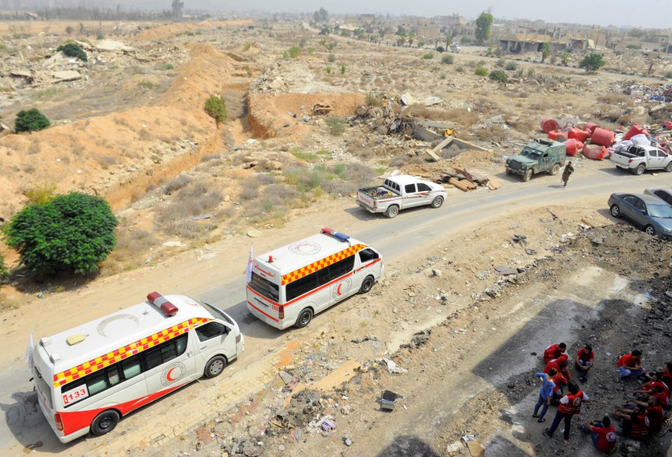 A Syrian Arab Red Crescent convoy waits at the entrance of the besieged Damascus suburb of Daraya
