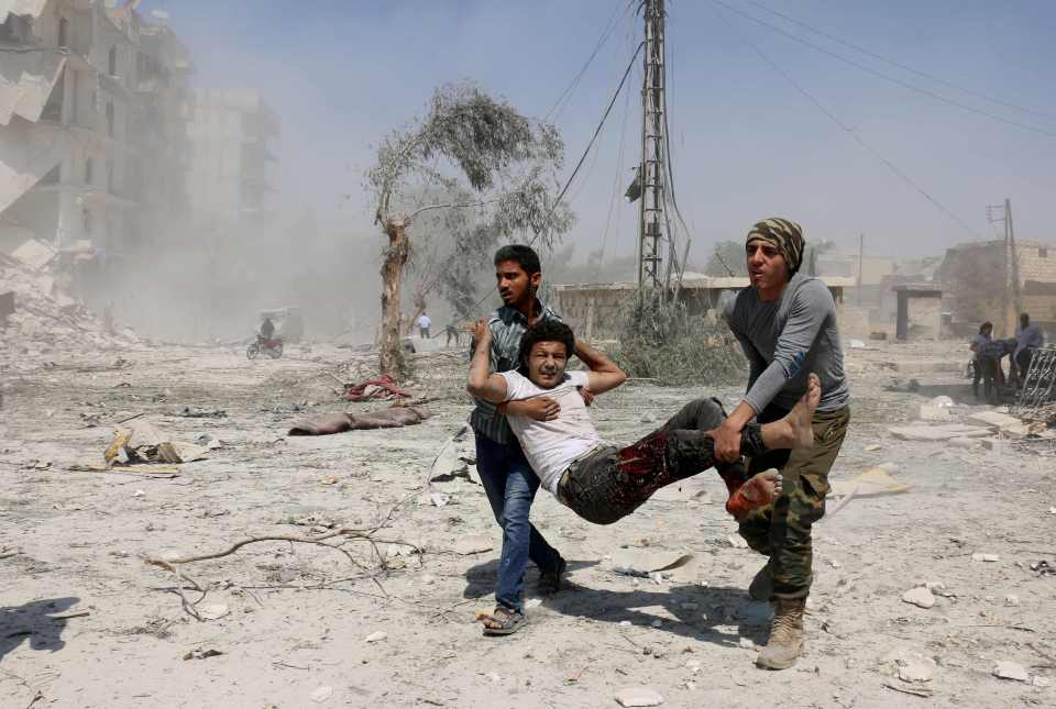 Two rescuers carry an injured man to safety after helicopter bombing in rebel-held Aleppo