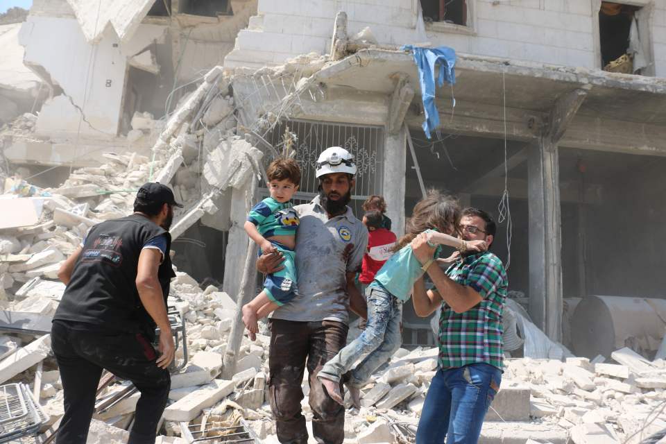Syrian civilians and a rescue worker evacuate children in Maadi district of eastern Aleppo after barrel bomb attack on wake