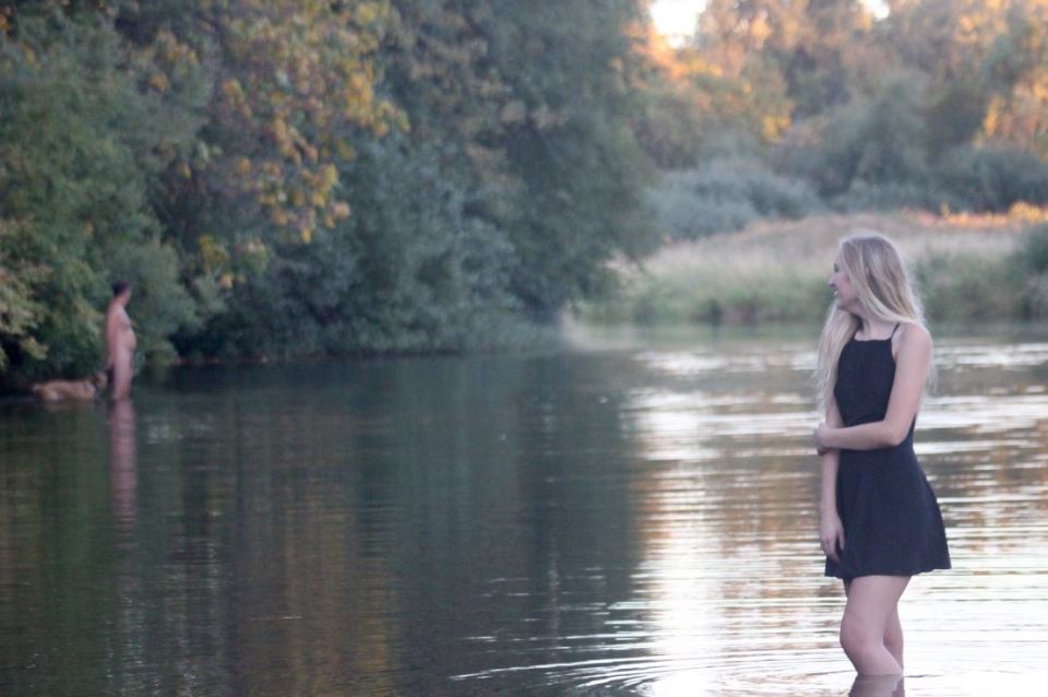 High school teen laughs as starkers swimmer larks around with his dog