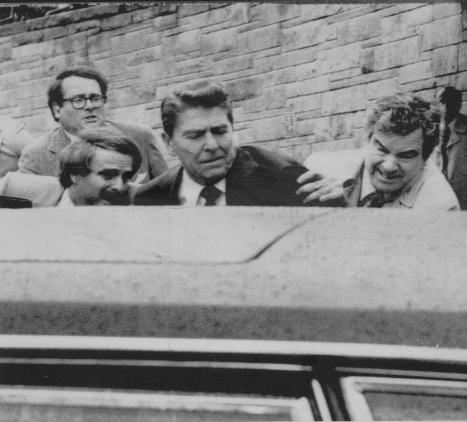 Secret Service Agents shove President Reagan into his limosine after he was shot at outside a Washington hotel