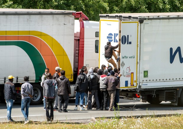 Migrants climb in the back of a lorry