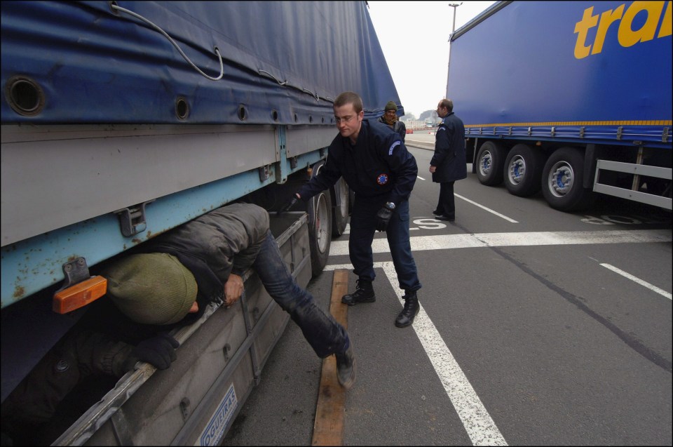 Police officers arrest migrants who are trying to reach the UK