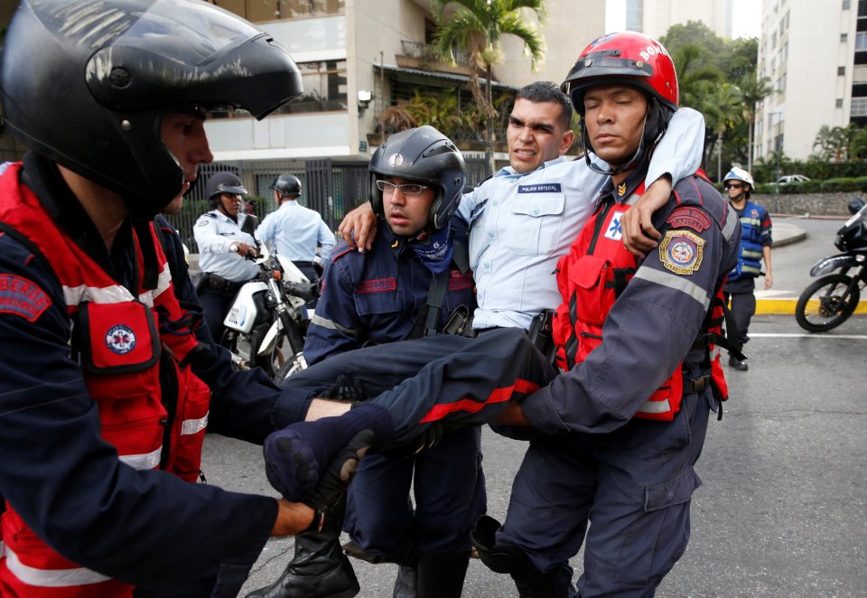 An injured police officer is carried by paramedics during clashes with opposition supporters after a rally to demand a referendum to remove Venezuela's President Maduro in Caracas