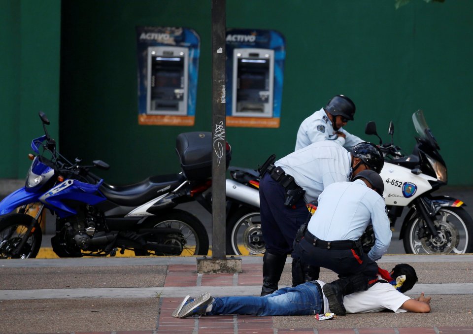 Police officers detain a protester during a rally to demand a referendum to remove Venezuela's President Maduro in Caracas