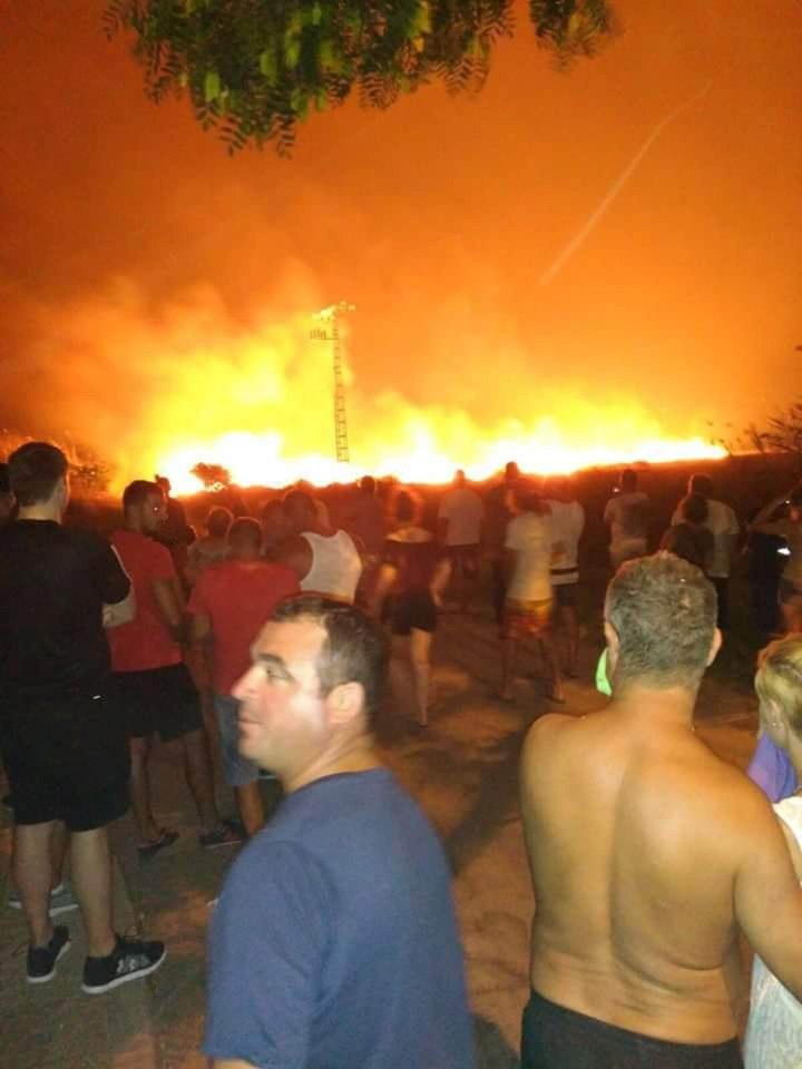 Locals look on in amazement at the raging fires in the distance