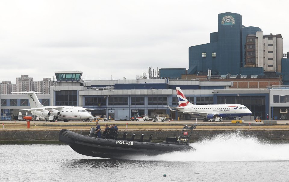 A police dinghy sails past as aircraft stand idle at City Airport 