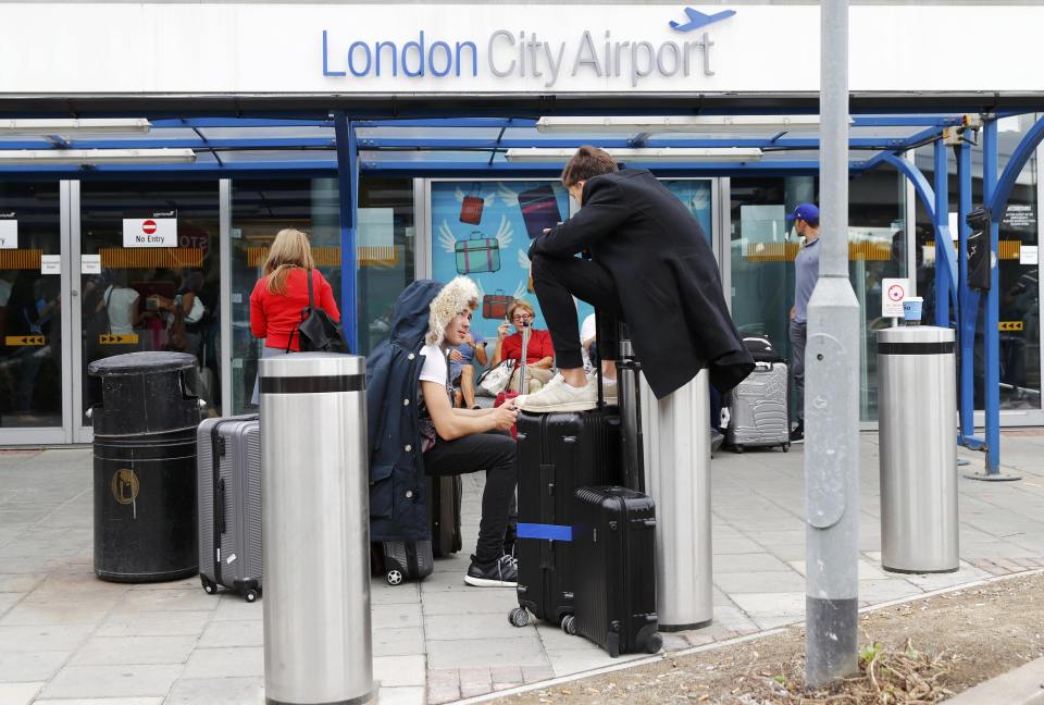 People could be seen sitting on bollards and their luggage as they waited for news