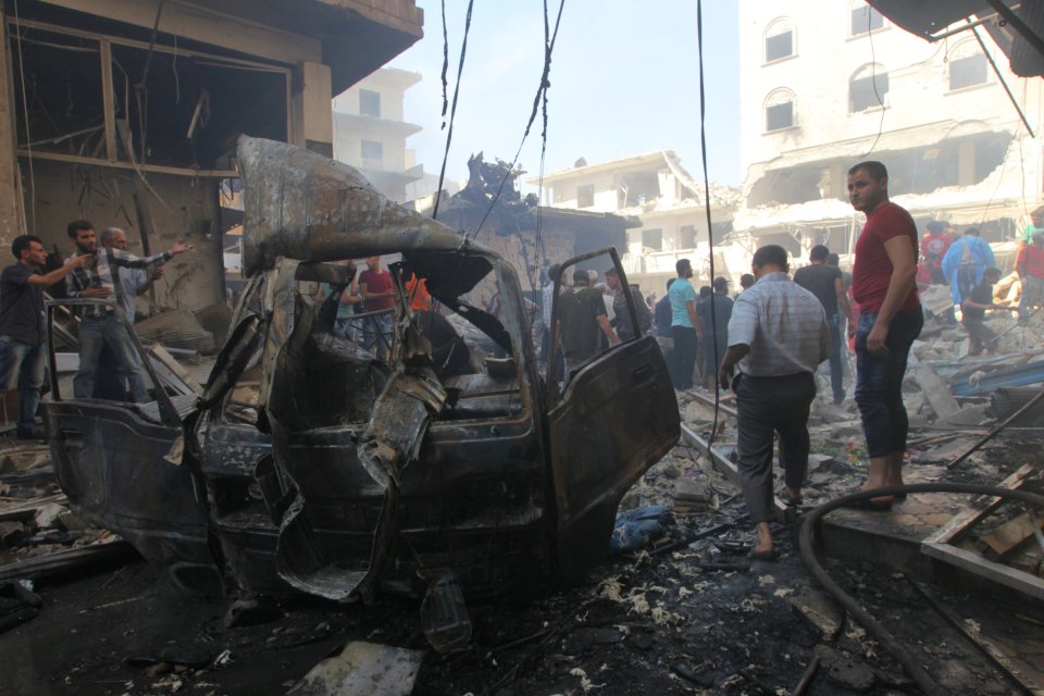 Residents inspect a damaged site after airstrikes on a market in the rebel controlled city 