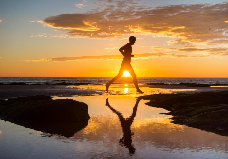 A jogger on Seaton Carew beach as the sky explodes with colour at sunrise on a glorious Monday morning on the north east coast